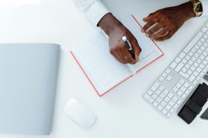 A man writing notes in an orange notebook